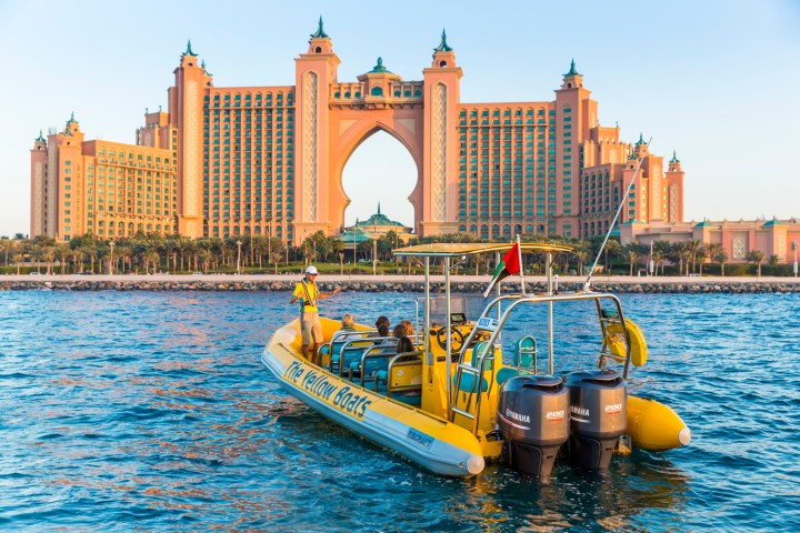 a small boat in a body of water with Atlantis, The Palm in the background